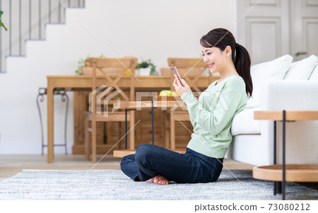 Young woman doing a smartphone in the living room 73080212