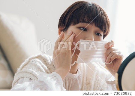 一個女人拿著口罩,擔心皮膚粗糙 一個女人拿著口罩,擔心皮膚粗糙 73080982