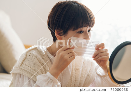 一個女人拿著口罩，擔心皮膚粗糙 73080988