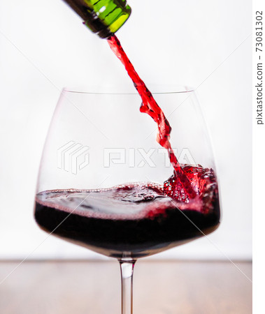 Red wine pouring to the glass, white background Red wine pouring to the glass, white background 73081302