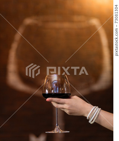 Woman holding red wine glass with glass shape background Woman holding red wine glass with glass shape background 73081304