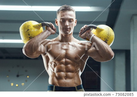 Fitness man pumping up muscles with kettlebell Fitness man pumping up muscles with kettlebell 73082085
