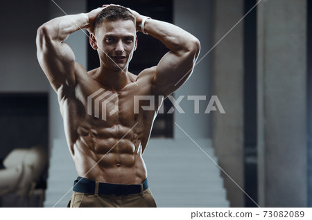 Fitness man pumping up abs muscles in gym 73082089