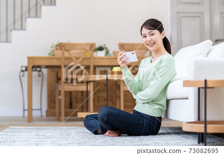 A young woman watching a video on her smartphone A young woman watching a video on her smartphone 73082695