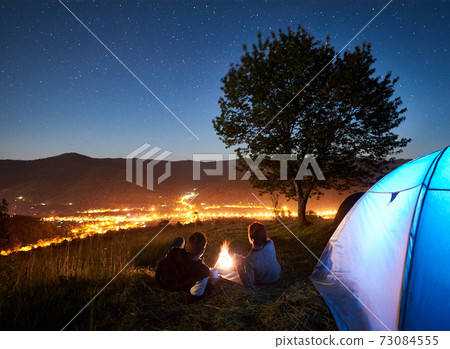 Couple tourists resting at night camping under stars 73084555