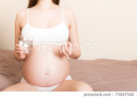 woman holding pill and glass of fresh pure water. Healthy millennial women taking antioxidant medicine vitamins, healthcare concept woman holding pill and glass of fresh pure water. Healthy millennial women taking antioxidant medicine vitamins, healthcare concept 73087588