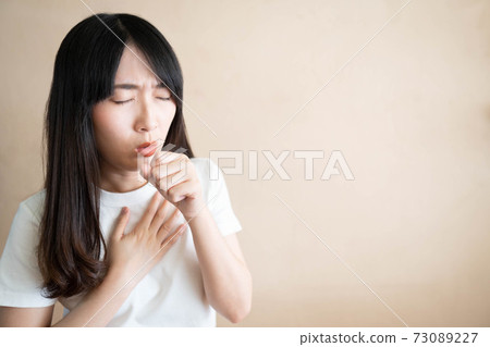Young ill female have a cough and sore throat over white background. Causes of cough include pneumonia, bronchitis, allergy, asthma, COPD, TB or respiratory tract infection. Copy space. Health care. Young ill female have a cough and sore throat over white background. Causes of cough include pneumonia, bronchitis, allergy, asthma, COPD, TB or respiratory tract infection. Copy space. Health care. 73089227