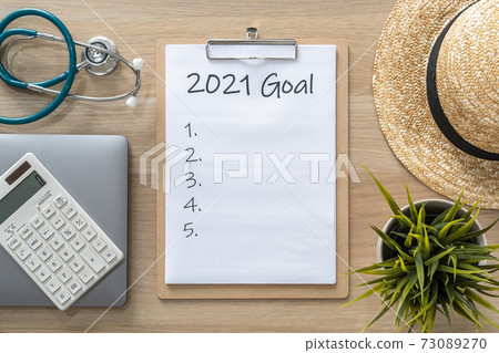 2021 goals on clipboard medical note pad for new year reminder list of yearly planner, health plan for work-life balance on desk background with computer, calculator, travel hat 2021 goals on clipboard medical note pad for new year reminder list of yearly planner, health plan for work-life balance on desk background with computer, calculator, travel hat 73089270
