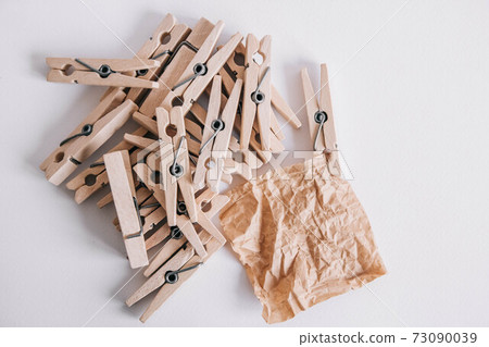Woodenl clothespins, paper clip and brown sticker on white background. Isolated on white. View from above. Place for your text 73090039