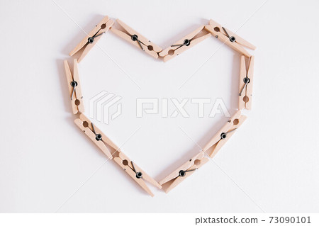 Wooden clothespins on white background which are folded in the form of heart icon. View from above. 73090101