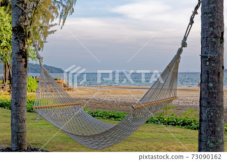 A relaxing rope hammock tied between two palm trees 73090162