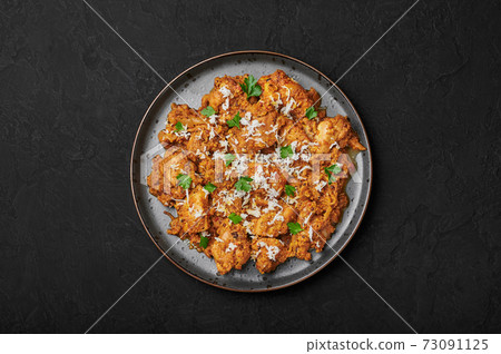 Mangalorean Chicken Sukka on black plate on dark slate table top. Indian cuisine coconut curry dish 73091125