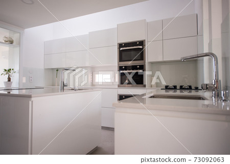White organised kitchen with modern elements in an apartment White organised kitchen with modern elements in an apartment 73092063