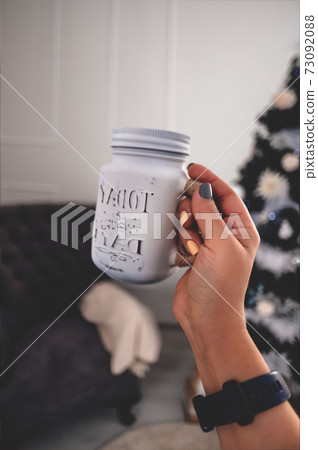 A glass jar with a drink in the hands of a woman. The lifestyle, the atmosphere of Christmas Copy space for your text. 73092088