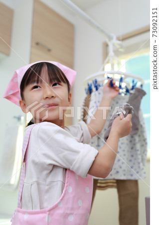 A 5-year-old girl helping to dry the clothes 73092151