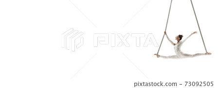 Young female acrobat, circus athlete isolated on white studio background. Training perfect balanced in flight 73092505