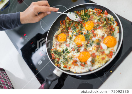 In the course of making breakfast with fresh eggs and vegetables 73092586