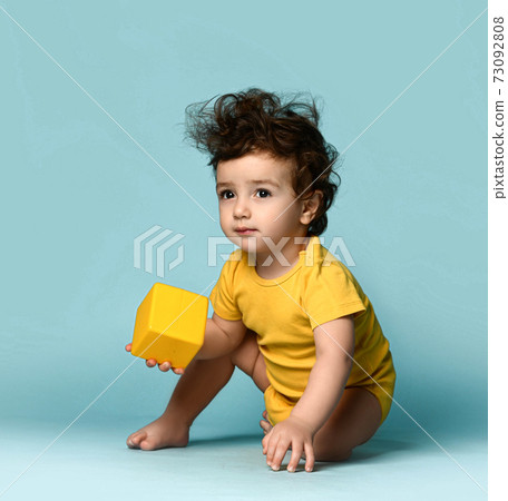 Small cute curly hairy baby boy toddler in yellow 73092808