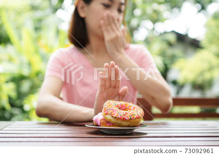 The beautiful Asian healthy middle aged woman sitting on the balcony beside the garden and Refuse to eat the nut. Concept of health care and nutritious food The beautiful Asian healthy middle aged woman sitting on the balcony beside the garden and Refuse to eat the nut. Concept of health care and nutritious food 73092961
