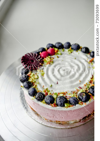 Raw vegan blueberry cake decorated with berry. Strawberry filling jelly vegetarian cashew cream cheesecake gluten free. Lactose sugar free holiday birthday desert. Indoor photo Raw vegan blueberry cake decorated with berry. Strawberry filling jelly vegetarian cashew cream cheesecake gluten free. Lactose sugar free holiday birthday desert. Indoor photo 73093699
