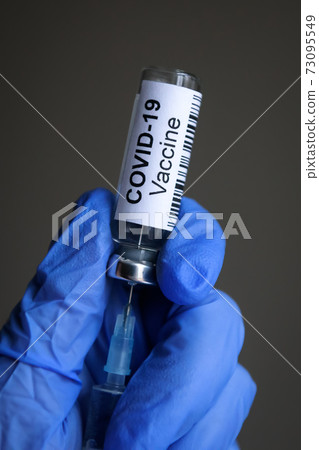 COVID-19 coronavirus vaccine and syringe in doctor`s hands 73095549