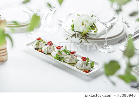 Fresh burata cheese with tomatoes and herbs on white plate Fresh burata cheese with tomatoes and herbs on white plate 73096946