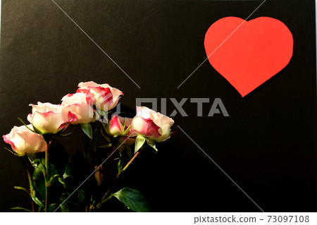 On the black surface of the leaf lies a bouquet of fresh flowers of roses and a red heart in the upper corner. Valentine's day postcard. On the black surface of the leaf lies a bouquet of fresh flowers of roses and a red heart in the upper corner. Valentine's day postcard. 73097108