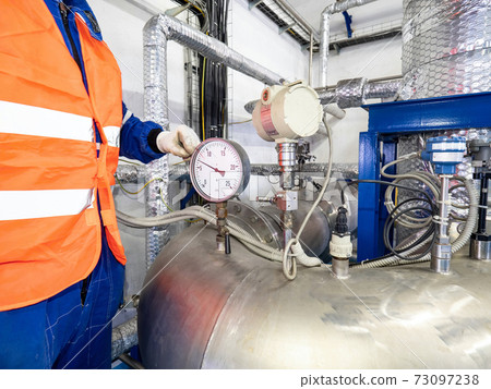 Man worker at chrome pipe with pressure and temperature control. 73097238