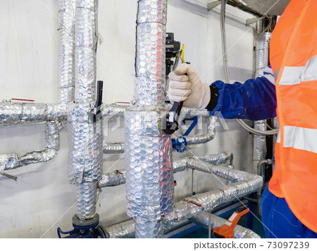 Employee open or close manual ball valve on thermally insulated piping 73097239