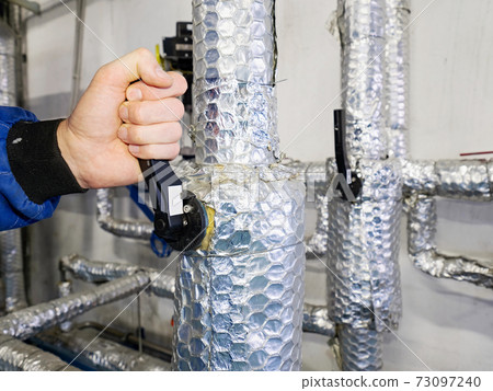 Employee open or close manual ball valve on thermally insulated piping 73097240
