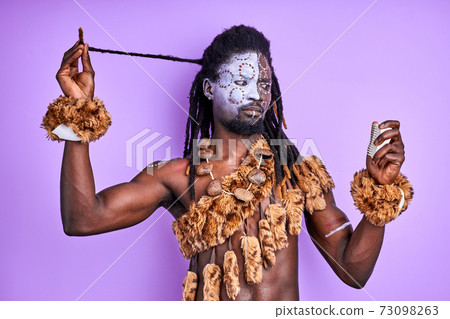 funny shaman tribal male trying to understand how to use modern combs for hair 73098263