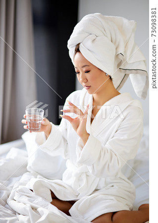 beautiful asian pregnant woman taking a medicine pill of vitamin while sitting on bed beautiful asian pregnant woman taking a medicine pill of vitamin while sitting on bed 73098381