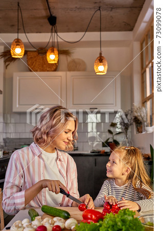 attractive young single mother making a salad in the kitchen with her daughter attractive young single mother making a salad in the kitchen with her daughter 73099078