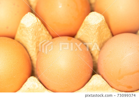 few yellow eggs in a tray close up few yellow eggs in a tray close up 73099374
