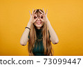 Making glasses fingers, looking at camera, smiling, funny, hold hands near eyes 73099447