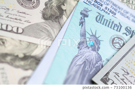 United States IRS Stimulus Check with Statue of Liberty Wearing Medical Face Mask Resting on Money 73100136