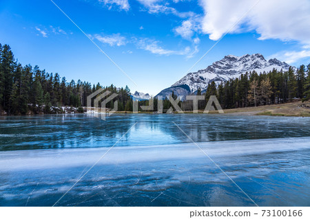 Johnson Lake frozen water surface in winter time. Snow-covered Cascade Mountain in background. Banff National Park, Canadian Rockies, Alberta, Canada. 73100166