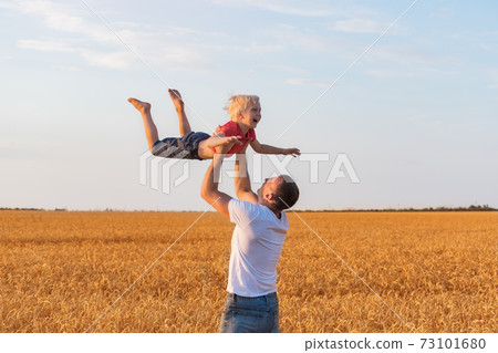 Father and child boy playing outdoors in countryside. Dad throws son. Father and child boy playing outdoors in countryside. Dad throws son. 73101680