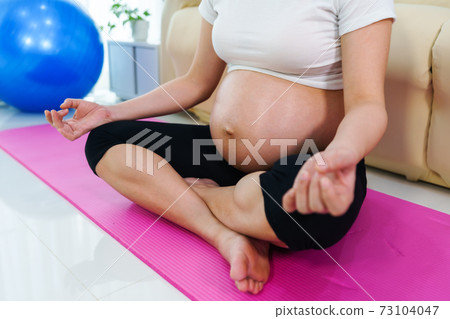 pregnant woman doing yoga exercise in living room at home 73104047