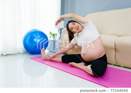 pregnant woman doing yoga exercise in living room at home 73104048