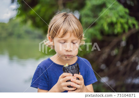 Boy eating Vietnamese Pork Banh Mi Sandwich in a black baguette 73104871