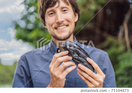 Man eating Vietnamese Pork Banh Mi Sandwich in a black baguette 73104873