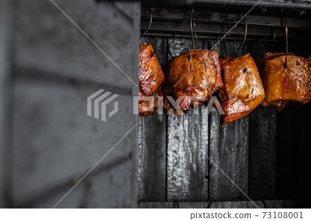 Close up of smoked meat and belly or beech meat with dark crust in the smokehouse or smoker, food concept Close up of smoked meat and belly or beech meat with dark crust in the smokehouse or smoker, food concept 73108001