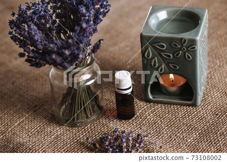 Aroma lamp with an aromatic oil and burning candle with bucket of lavender in the glass, aromatherapy concept 73108002