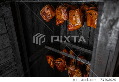 Close up of smoked meat and belly or beech meat with dark crust in the smokehouse or smoker, food concept Close up of smoked meat and belly or beech meat with dark crust in the smokehouse or smoker, food concept 73108020