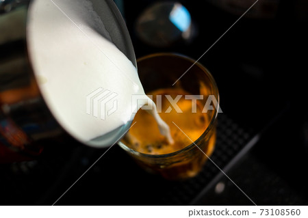 Close focus on pouring steam milk into shot of hot espresso coffee on glass cup. 73108560