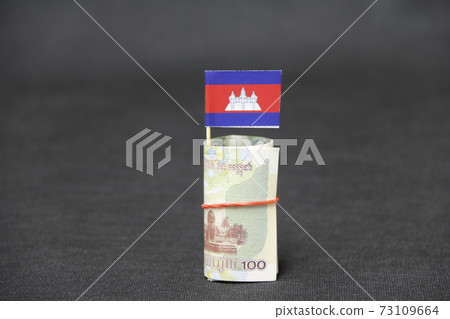 Rolled banknote money one hundred Cambodian Riel and stick with mini Cambodia flag Rolled banknote money one hundred Cambodian Riel and stick with mini Cambodia flag 73109664