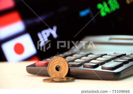 Japanese five Yen coins (JPY) on white floor with black calculator and digital board 73109666