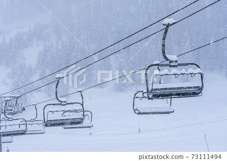 Empty ski slopes and ski lifts in Auron ski resort, France. During the winter holidays of 2020 December and 2021 January lifts are closed for skiing for adults due to the coronavirus pandemic.  73111494