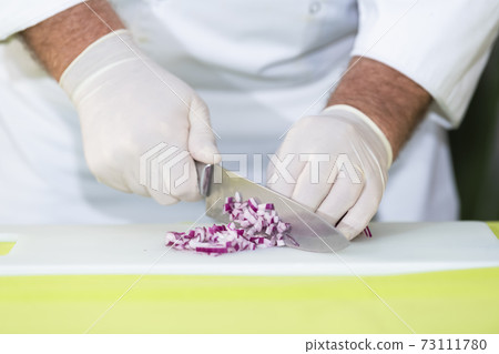 Chef cutting a red onion into dice Chef cutting a red onion into dice 73111780